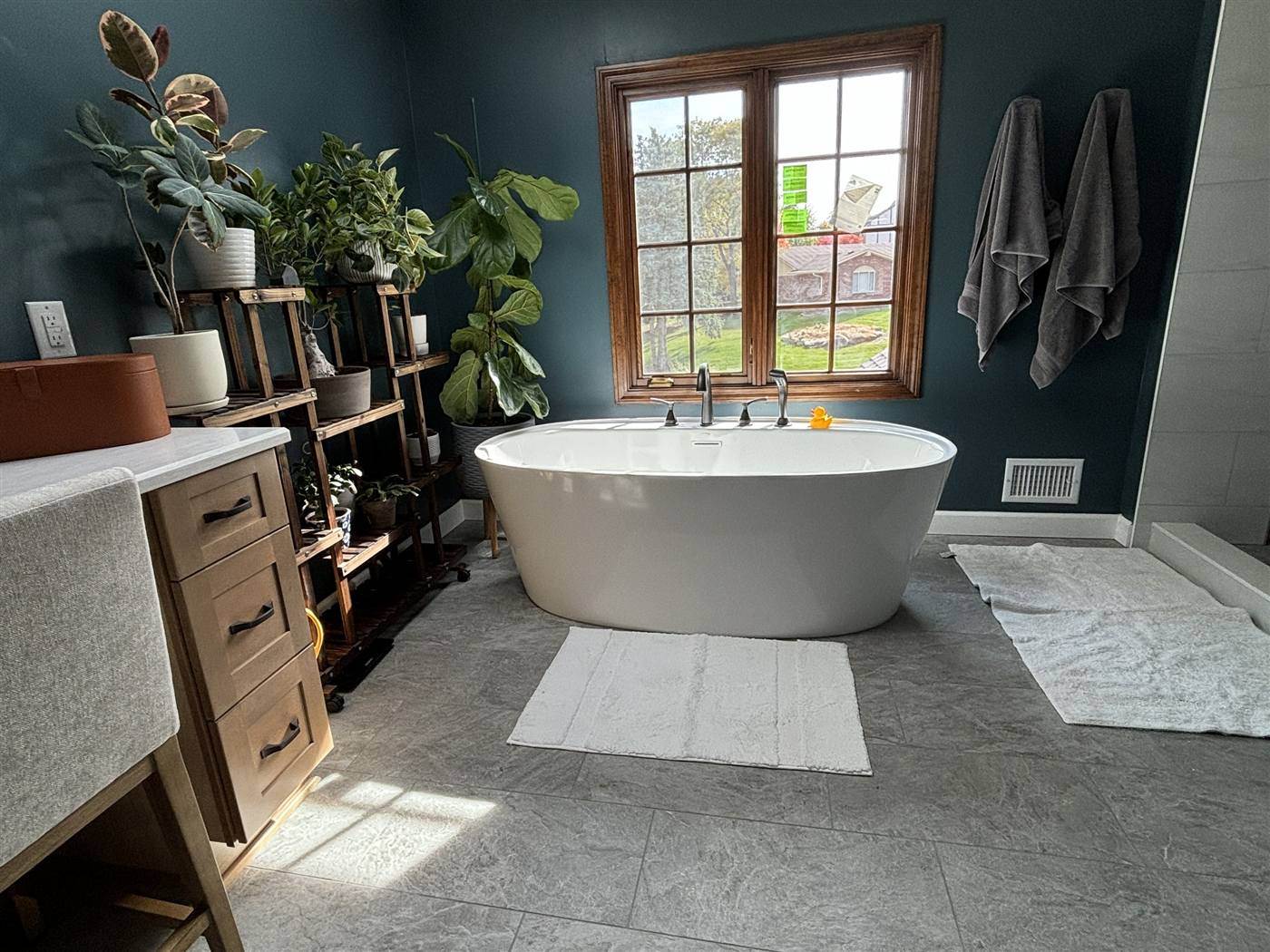 Freestanding tub under a window with deep blue walls