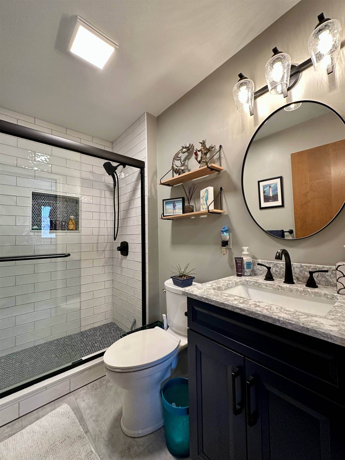 Hall bathroom with a black vanity and round mirror