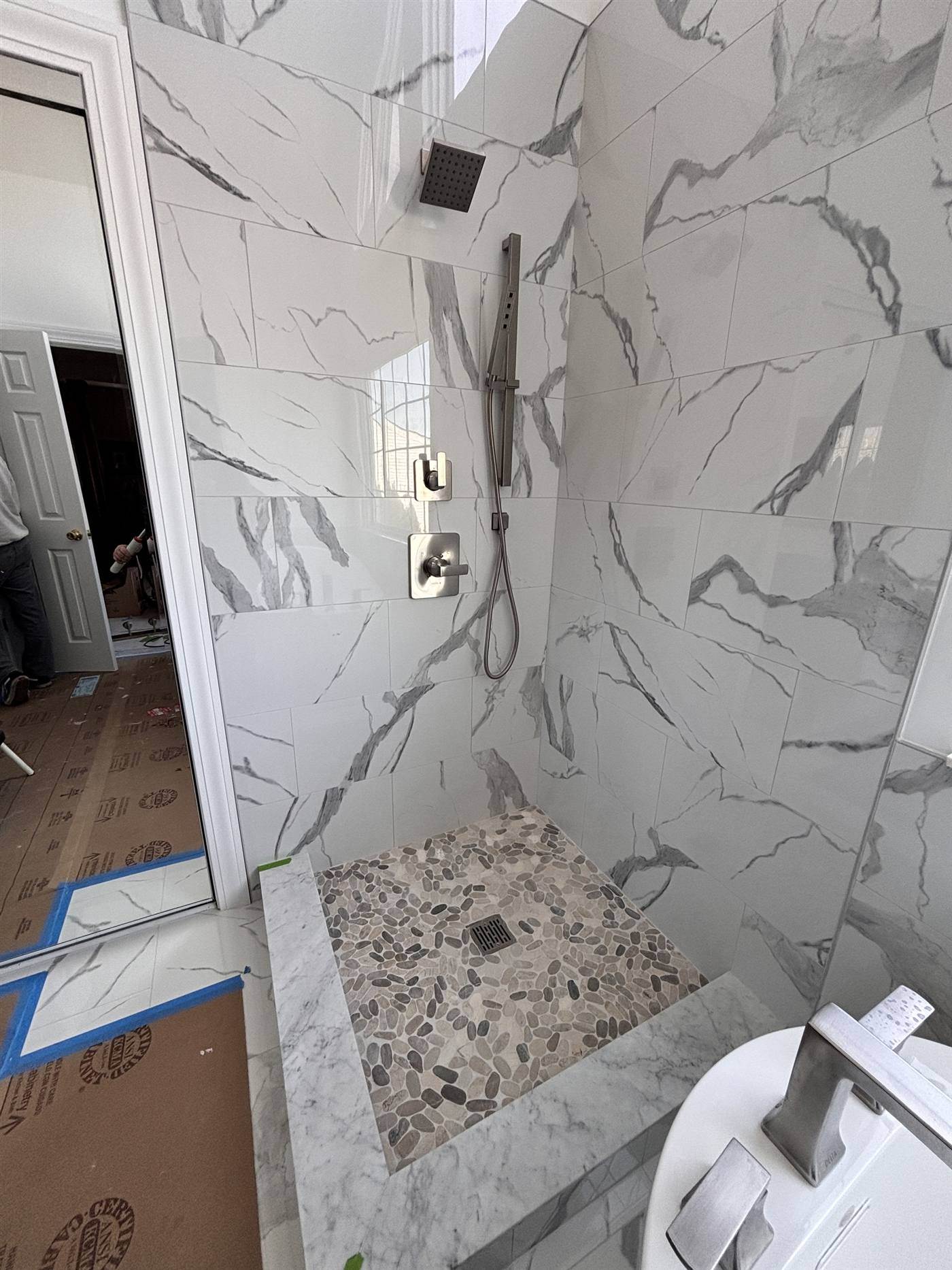 Marble-look walk-in shower with a pebble floor