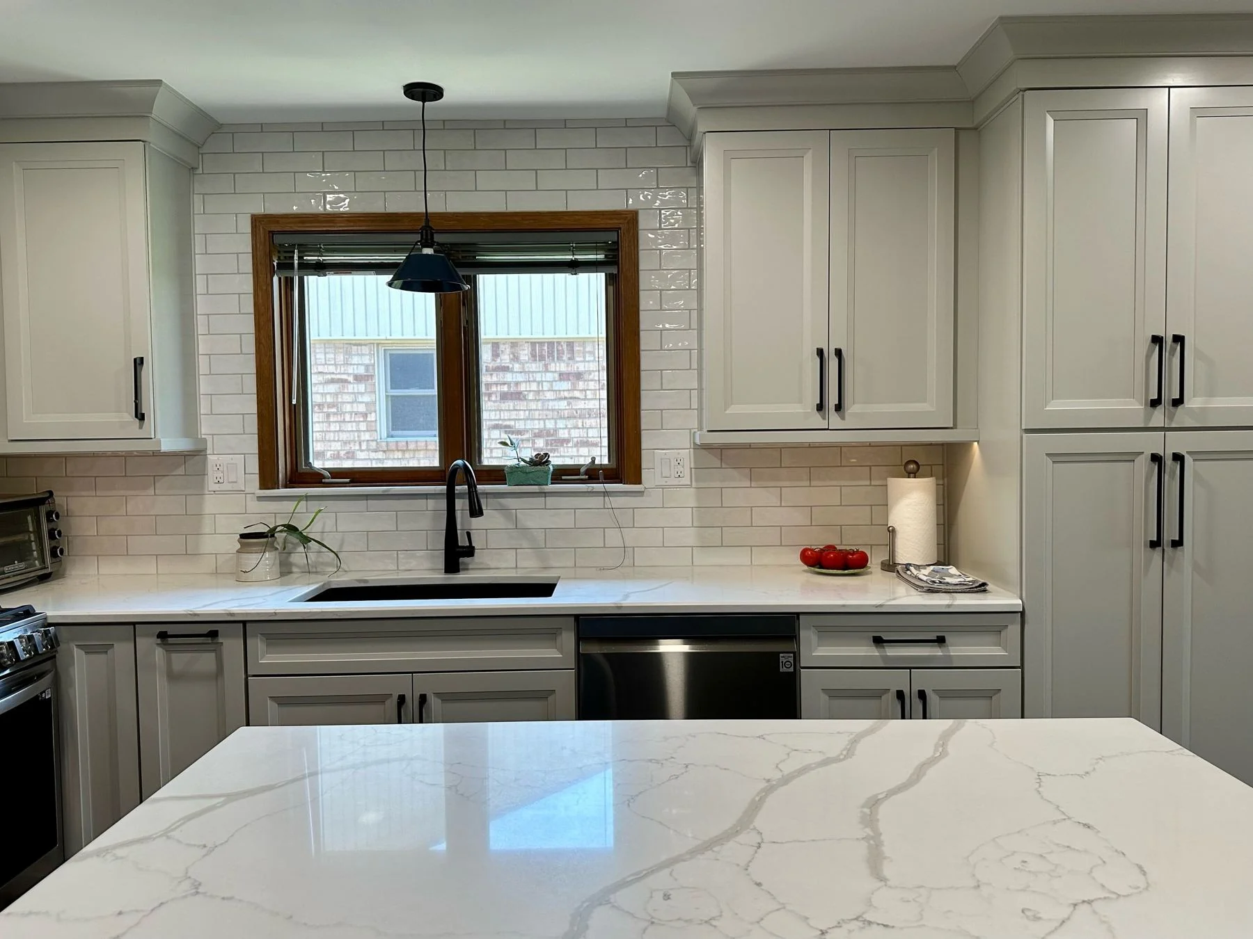 White kitchen with a veined quartz island, remodeled by HomeWorks
