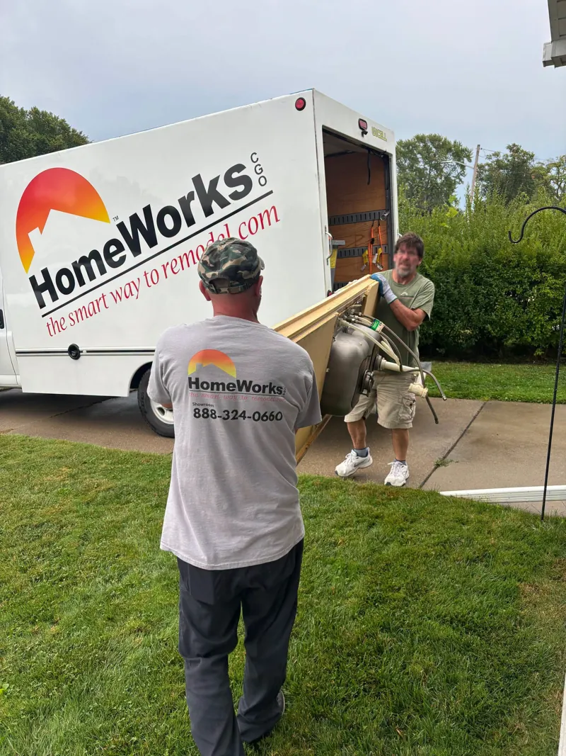 HomeWorks employees carrying materials beside the company truck